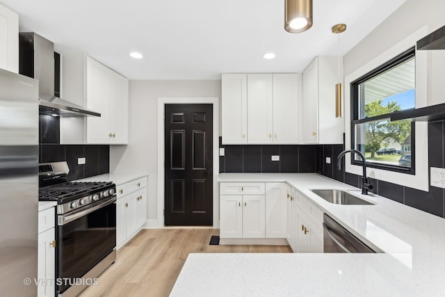 kitchen with sink, appliances with stainless steel finishes, hanging light fixtures, light hardwood / wood-style flooring, and white cabinets