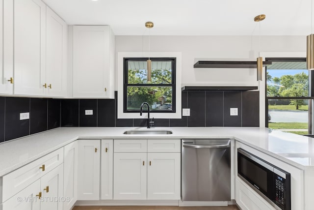 kitchen with built in microwave, hanging light fixtures, sink, white cabinets, and stainless steel dishwasher