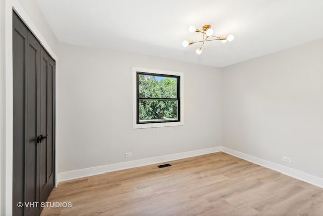 unfurnished room featuring light wood-type flooring and a notable chandelier