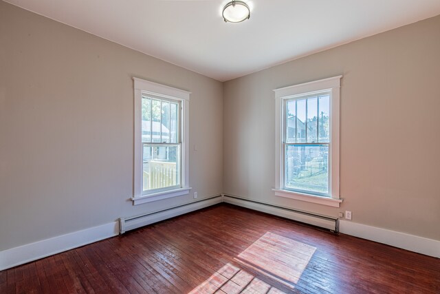 unfurnished room with baseboard heating, plenty of natural light, and hardwood / wood-style flooring