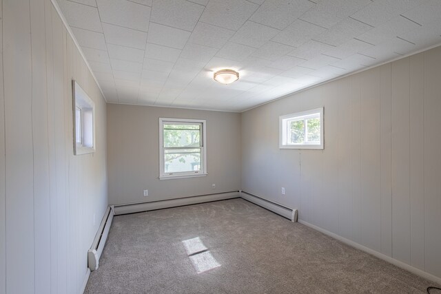 carpeted empty room with a baseboard radiator and wooden walls