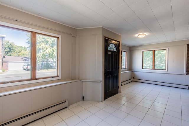 empty room with a wealth of natural light, baseboard heating, and light tile patterned floors