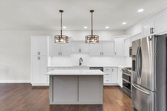 kitchen featuring dark wood-type flooring, white cabinets, decorative light fixtures, and stainless steel appliances