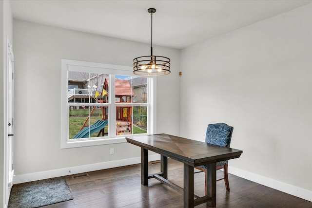 dining area with dark hardwood / wood-style floors and a notable chandelier