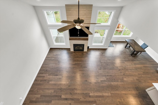 unfurnished living room featuring ceiling fan, dark hardwood / wood-style floors, and a towering ceiling