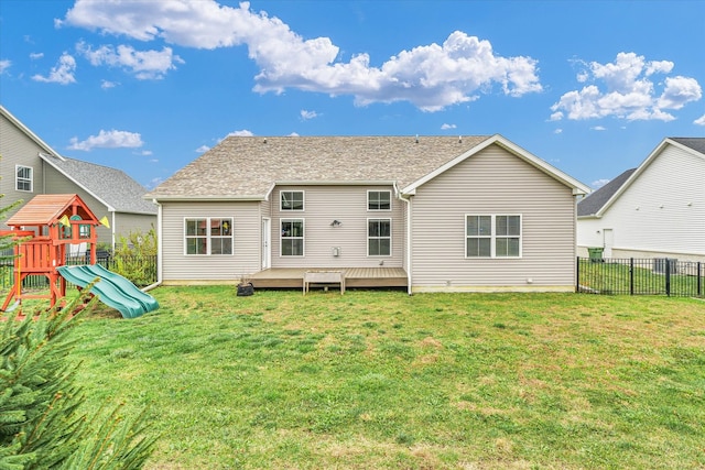 rear view of house featuring a playground, a lawn, and a deck