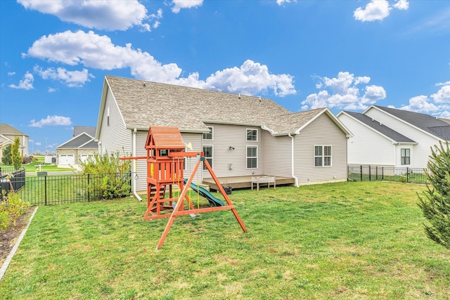 rear view of property with a playground, a yard, and a deck