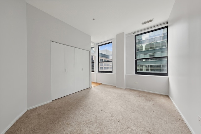 unfurnished bedroom with light carpet and a closet