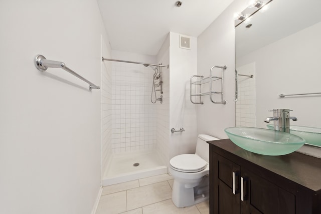 bathroom with tiled shower, tile patterned flooring, vanity, and toilet