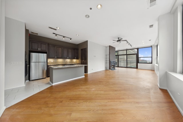 kitchen featuring dark brown cabinetry, ceiling fan, stainless steel fridge, light wood-type flooring, and decorative backsplash