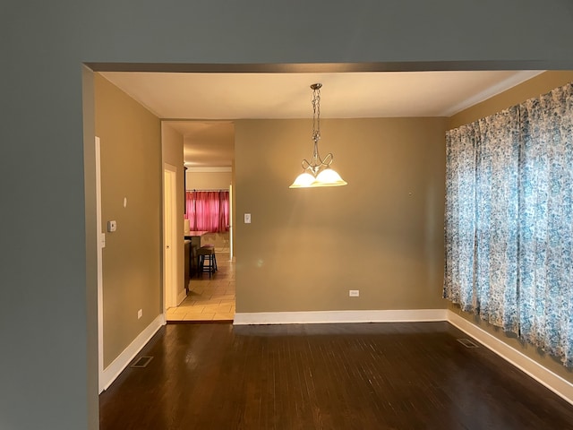 unfurnished room with dark hardwood / wood-style floors, crown molding, and an inviting chandelier