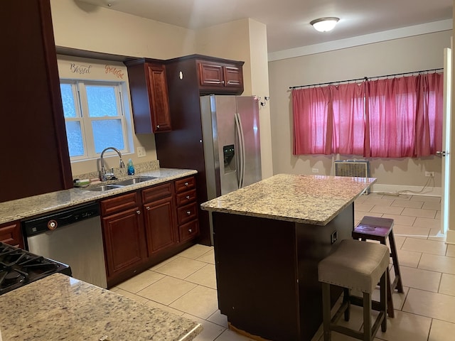 kitchen with stainless steel appliances, sink, a kitchen breakfast bar, light tile patterned floors, and a kitchen island