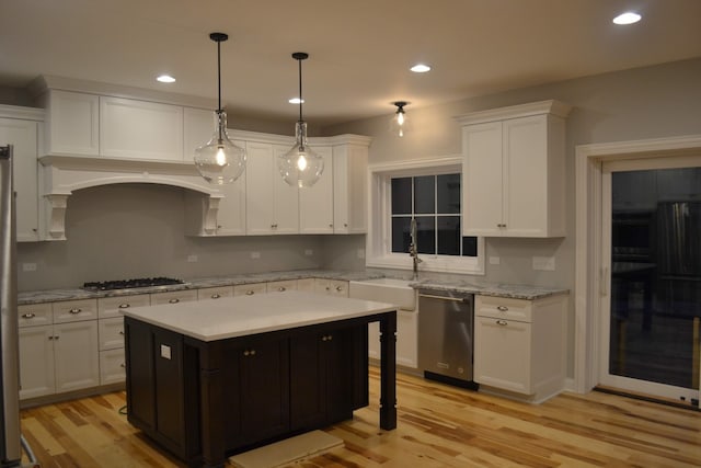 kitchen with light hardwood / wood-style floors, white cabinetry, appliances with stainless steel finishes, and a center island