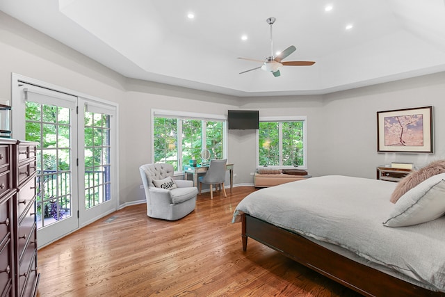 bedroom featuring access to exterior, wood-type flooring, ceiling fan, and a raised ceiling