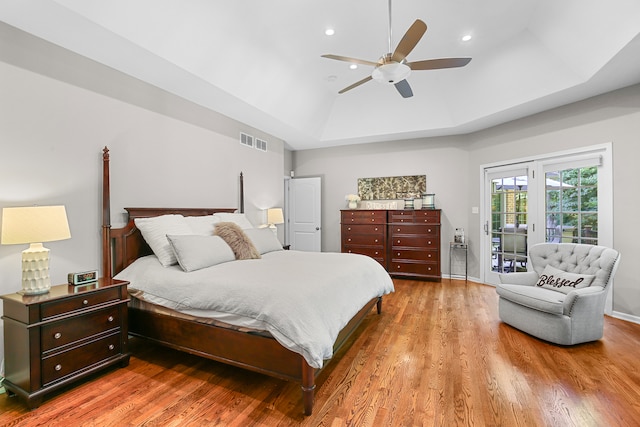 bedroom with access to outside, wood-type flooring, ceiling fan, and a raised ceiling