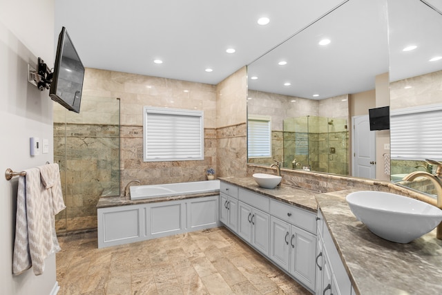 bathroom featuring independent shower and bath, vanity, and tile walls