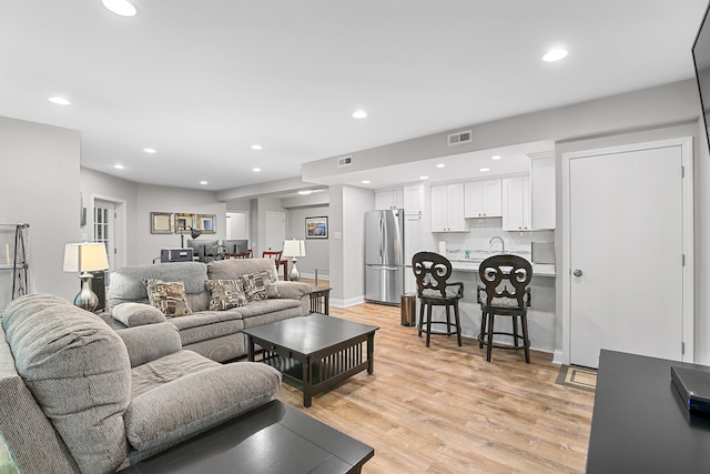 living room with light hardwood / wood-style flooring and sink