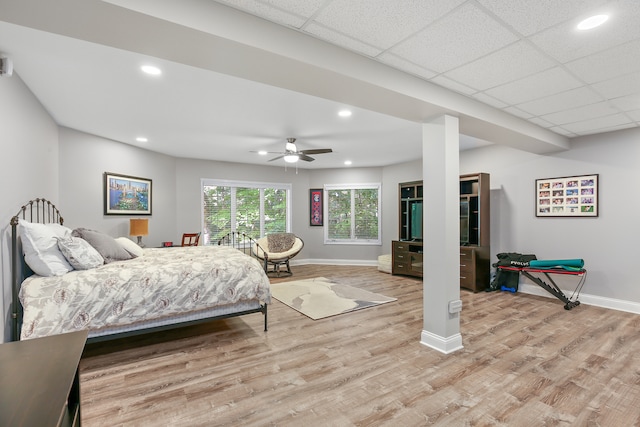 bedroom with a paneled ceiling, light wood-type flooring, and ceiling fan