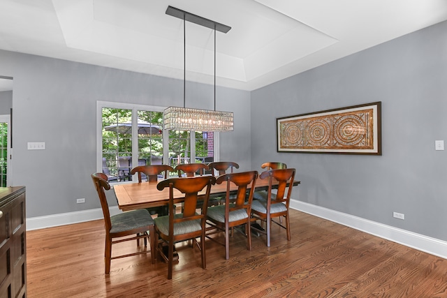 dining room featuring wood-type flooring, a tray ceiling, and an inviting chandelier