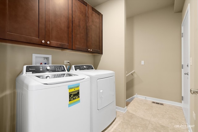 clothes washing area featuring washing machine and dryer and cabinets