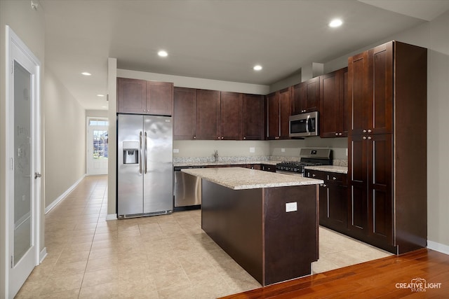 kitchen featuring a center island, stainless steel appliances, dark brown cabinets, sink, and light hardwood / wood-style flooring