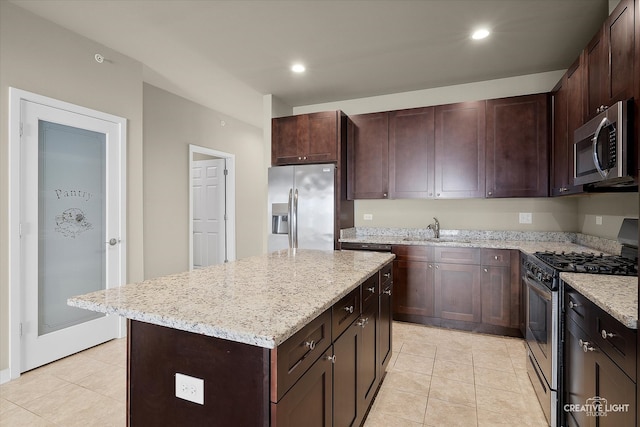 kitchen featuring sink, light tile patterned floors, a kitchen island, dark brown cabinets, and appliances with stainless steel finishes