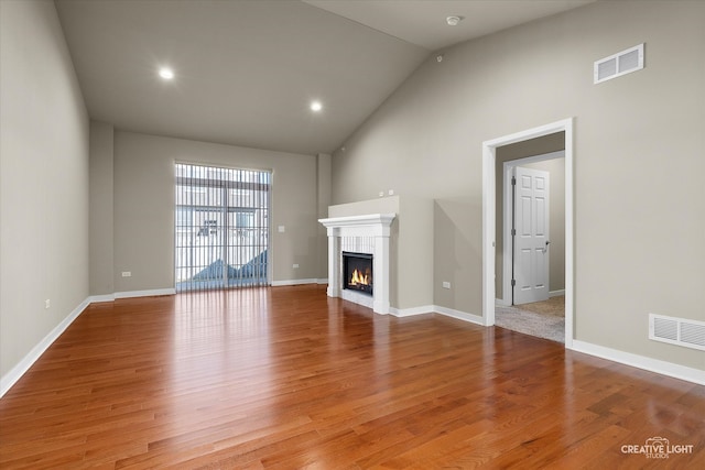 unfurnished living room with high vaulted ceiling and hardwood / wood-style floors