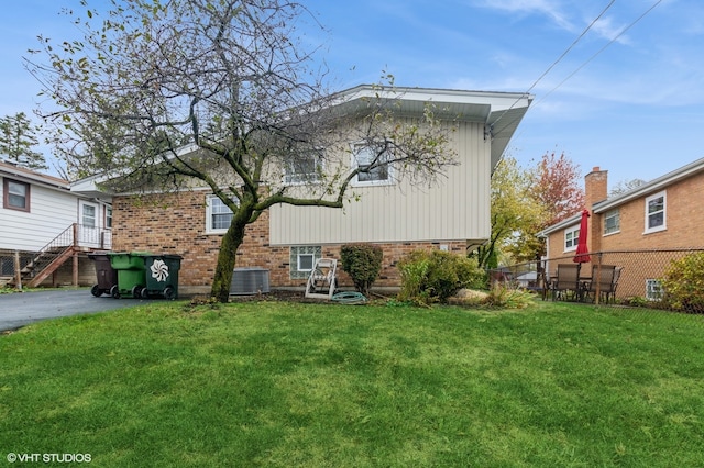 rear view of house with a lawn and cooling unit