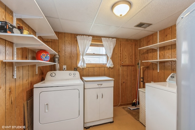 clothes washing area featuring wood walls and independent washer and dryer