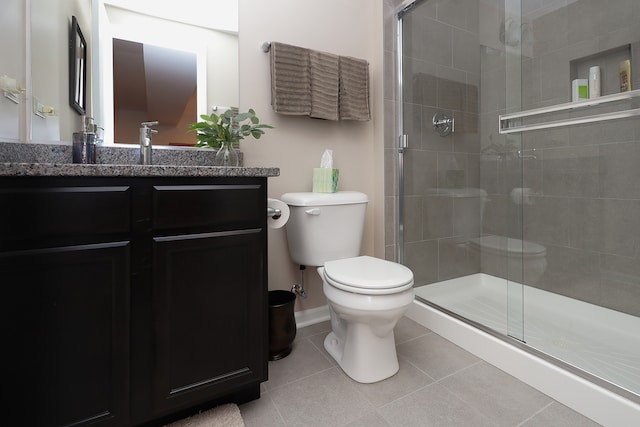 bathroom featuring tile patterned flooring, vanity, toilet, and a shower with shower door