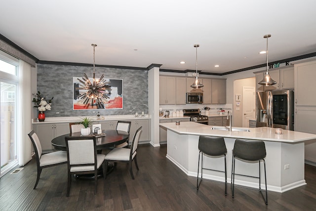 kitchen with appliances with stainless steel finishes, dark hardwood / wood-style flooring, gray cabinetry, a large island with sink, and hanging light fixtures