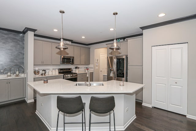 kitchen featuring pendant lighting, a center island with sink, sink, and appliances with stainless steel finishes