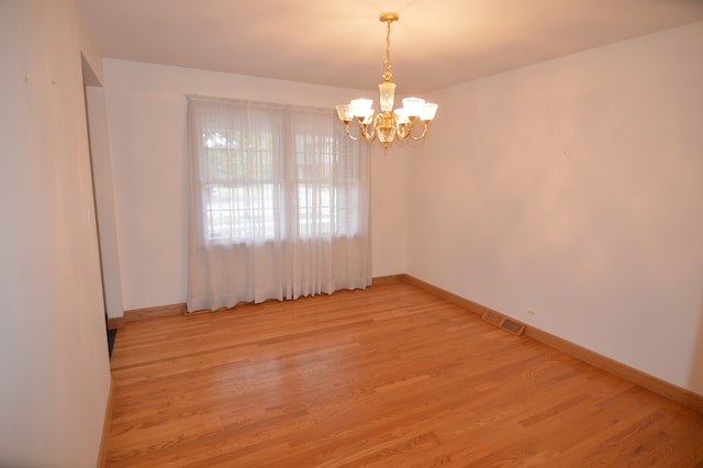 spare room with light hardwood / wood-style flooring and a notable chandelier