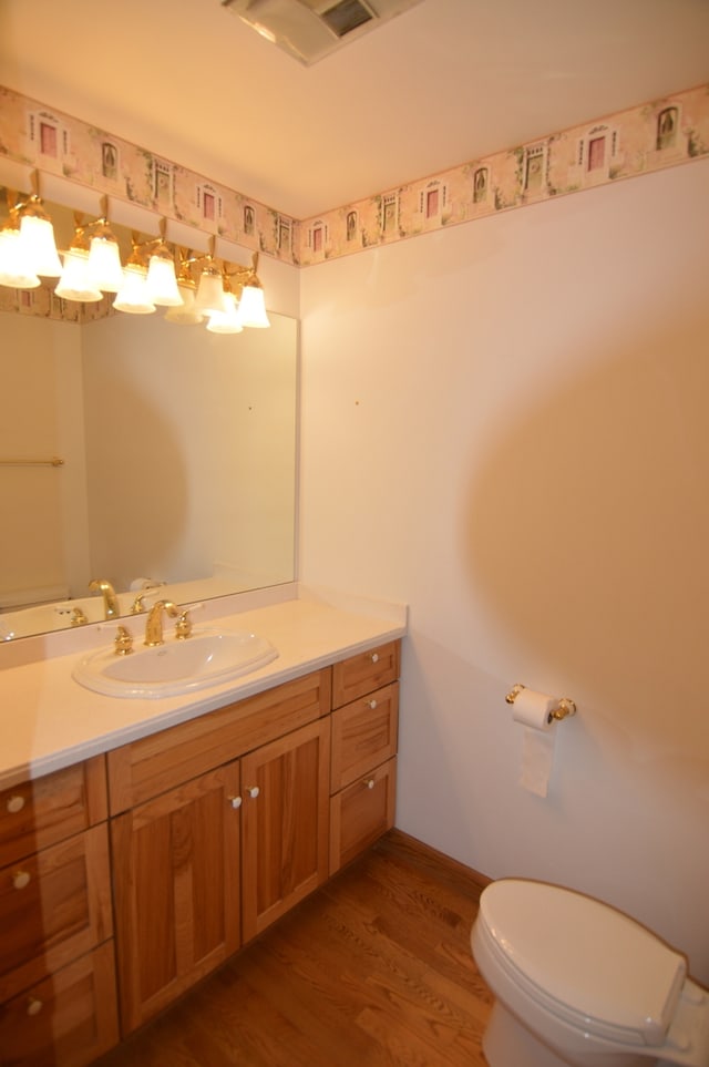 bathroom with hardwood / wood-style floors, vanity, and toilet