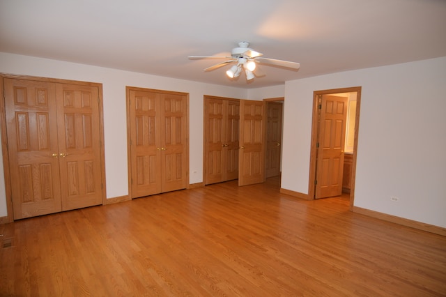 unfurnished bedroom featuring light hardwood / wood-style floors, ceiling fan, multiple closets, and ensuite bathroom