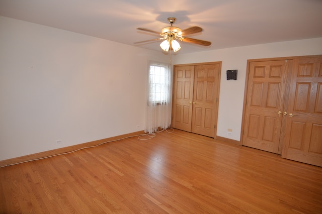 unfurnished bedroom featuring multiple closets, light hardwood / wood-style flooring, and ceiling fan