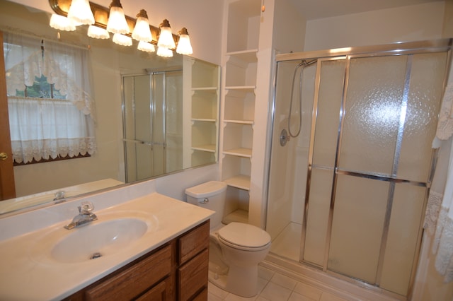 bathroom featuring toilet, vanity, tile patterned floors, and a shower with door