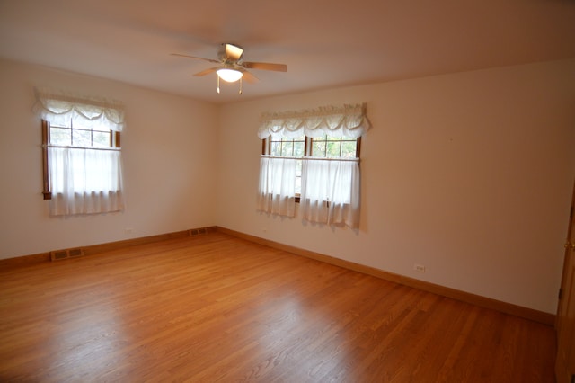 spare room featuring a wealth of natural light, wood-type flooring, and ceiling fan