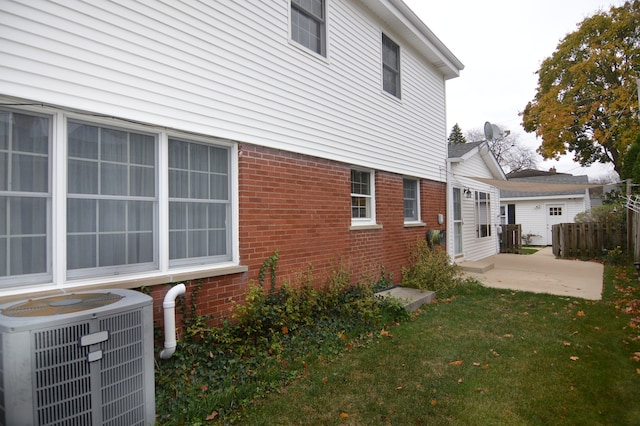 view of side of property featuring central air condition unit and a yard