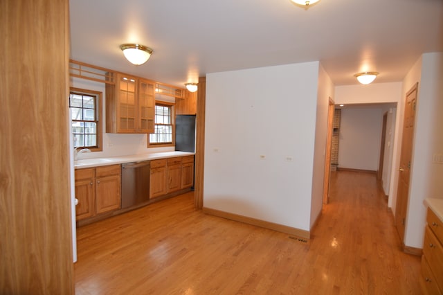 kitchen with stainless steel dishwasher and light hardwood / wood-style floors