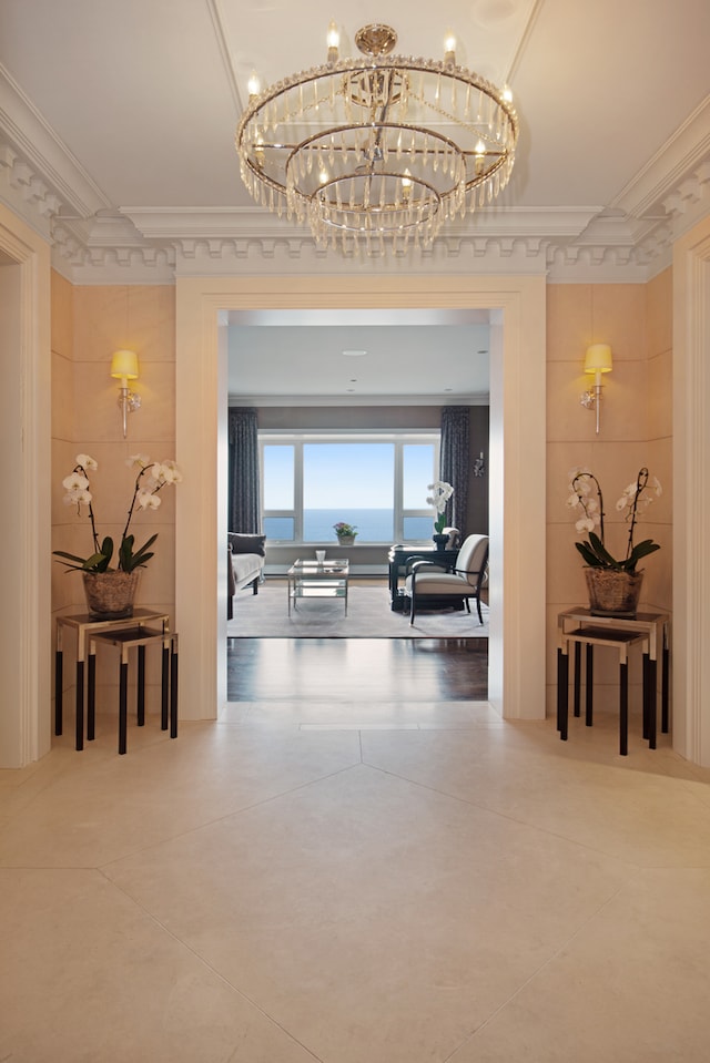 corridor featuring ornamental molding, a chandelier, and concrete floors