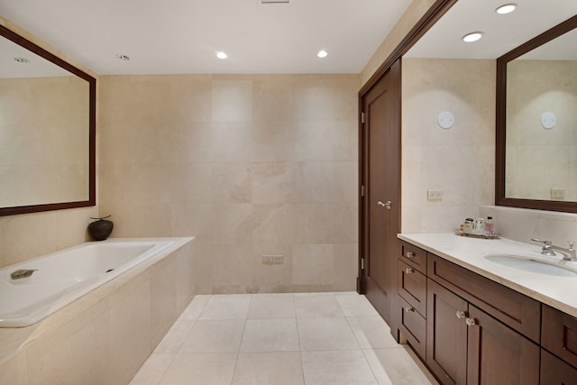 bathroom with tile walls, tile patterned flooring, a washtub, and vanity