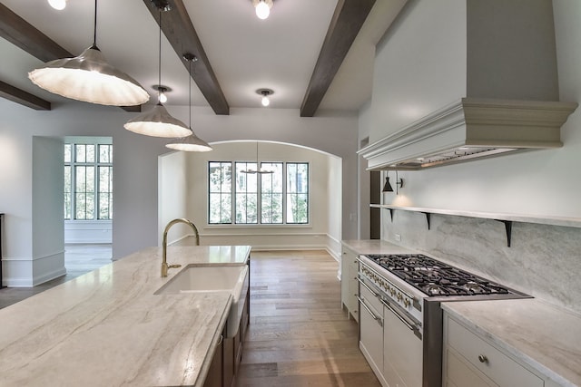 kitchen featuring custom exhaust hood, sink, beamed ceiling, decorative light fixtures, and light stone counters