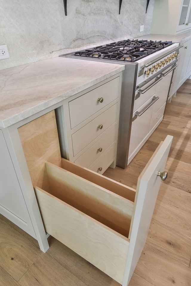 interior details with light hardwood / wood-style floors, high end range, and white cabinetry