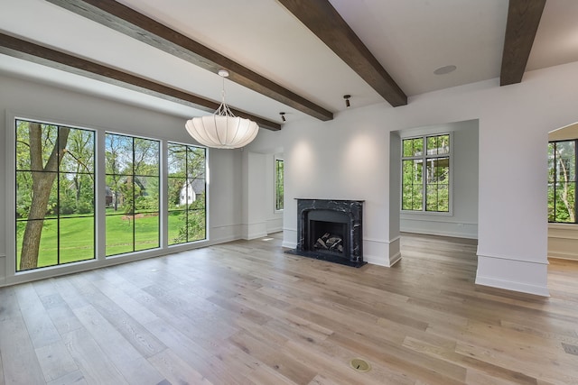 unfurnished living room with beam ceiling, a premium fireplace, and light hardwood / wood-style flooring