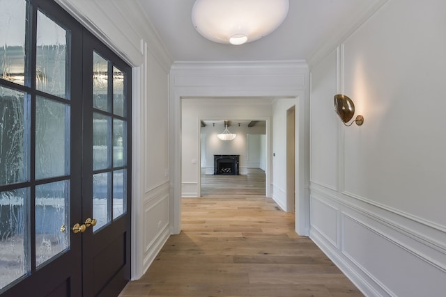 corridor with french doors, light wood-type flooring, and ornamental molding