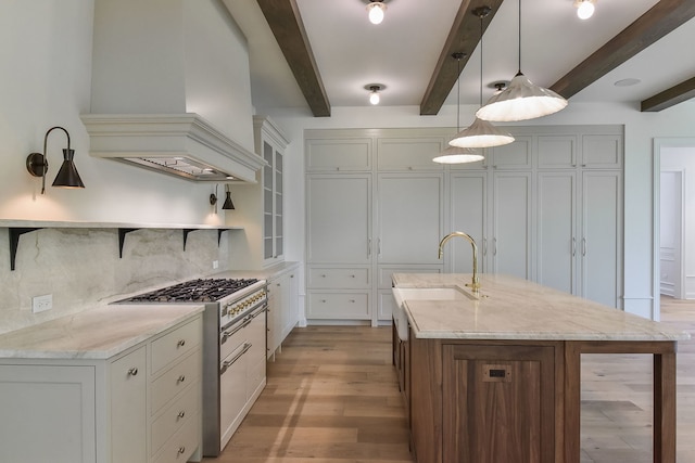 kitchen with beamed ceiling, light stone counters, premium range hood, and hanging light fixtures