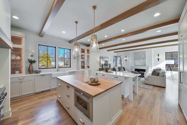 kitchen with beam ceiling, white cabinetry, a kitchen island, and stainless steel appliances