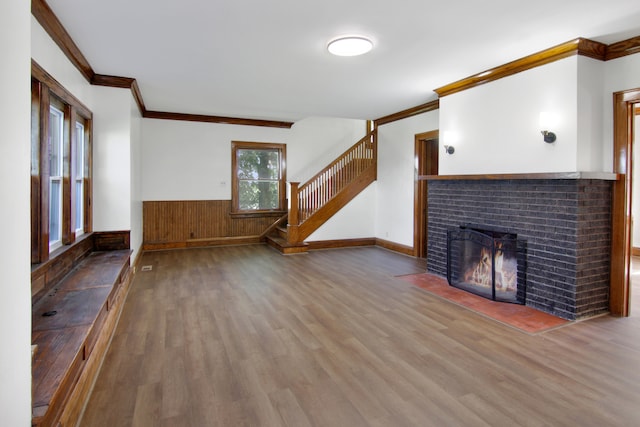 unfurnished living room with ornamental molding, hardwood / wood-style floors, a fireplace, and wood walls