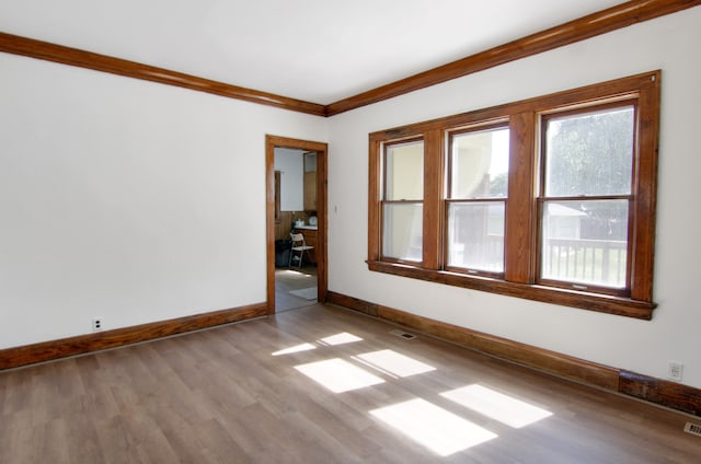 empty room with light hardwood / wood-style flooring and ornamental molding